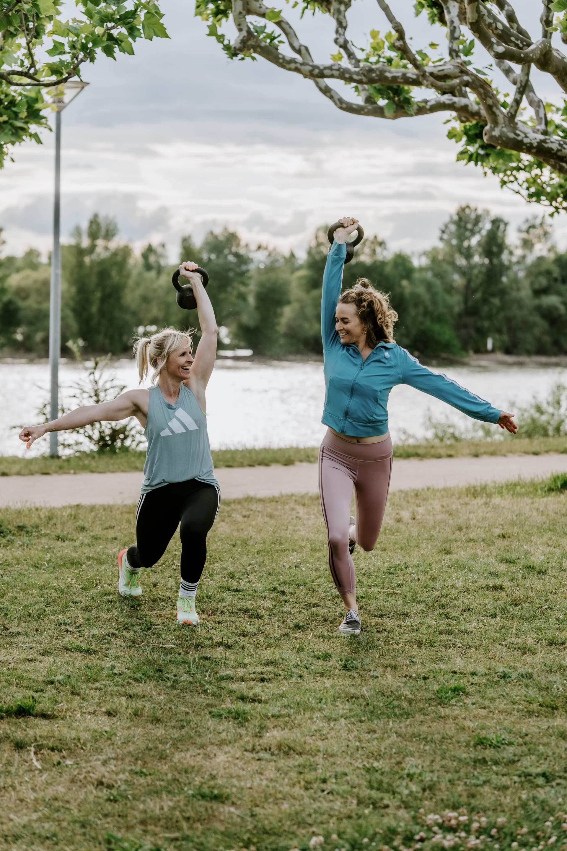 Zwei Kunden trainieren mit Kettlebells am Ufer eines Flusses mit Original Bootcamp