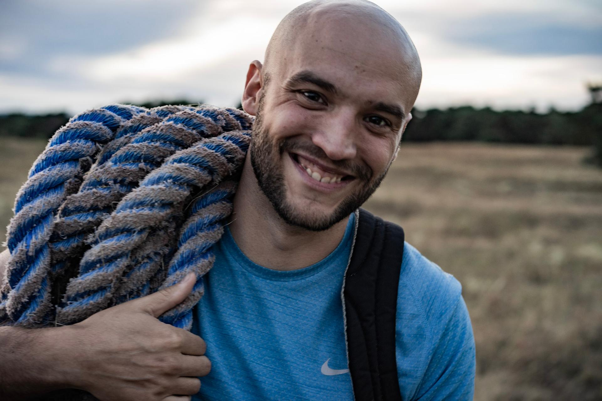 Trainer hat Seil auf der Schulter und lächelt in Kamera