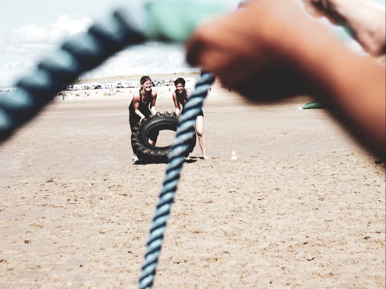 Teilnehmerinnen bei ihrer Bootcamp Einheit mit Reifen am Strand