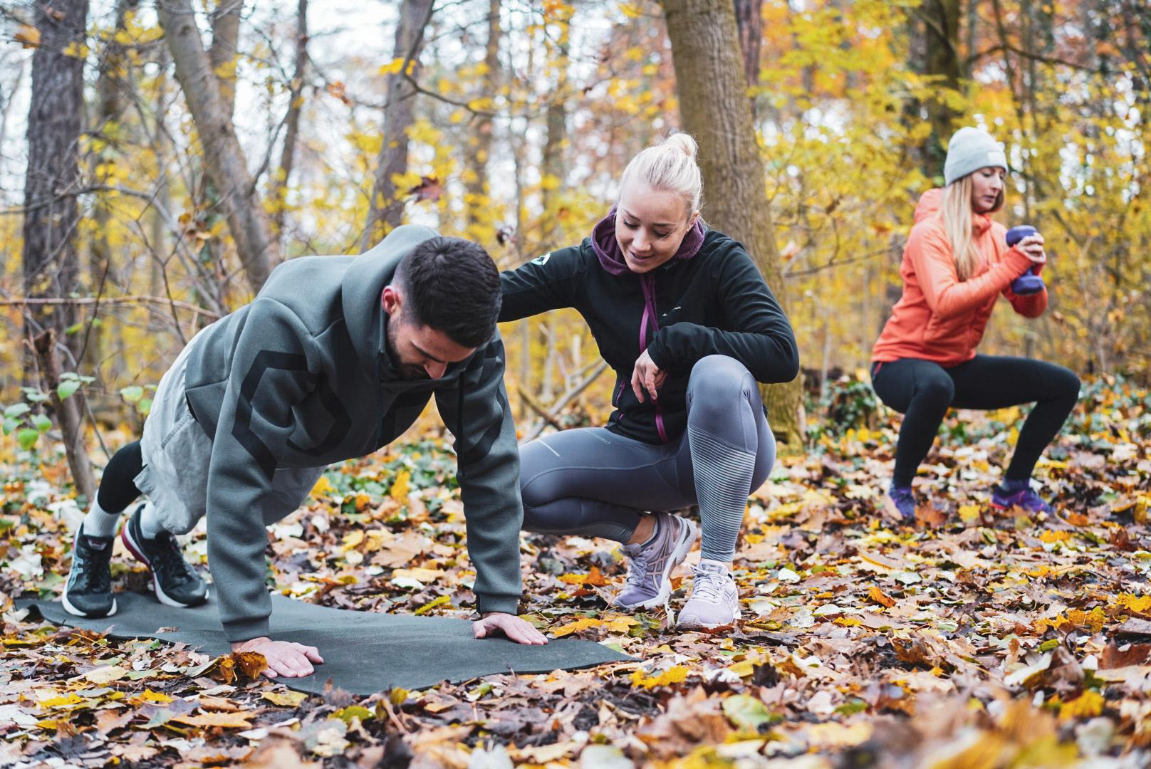 Outdoor Trainingsgruppe im Wald mit einer Personal Trainerin